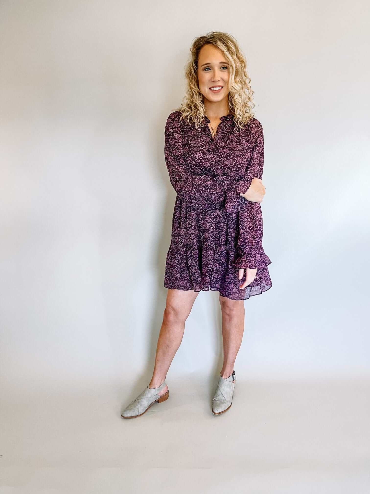 swing mini dress with three tiers in egg plant color with mauve floral print ruffled collar, tie detail on neck long flounce sleeves fully Lined
